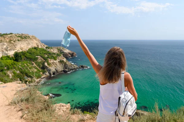 티셔츠를 가방을 소녀가 의약품 마스크를 기슭에 바다를 바라본다 — 스톡 사진
