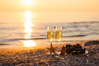 Deniz kıyısında Noel 'i kutluyoruz. Günbatımı arka planında Noel ağacı şeklinde iki bardak şampanya ve kurabiye. Ağaca ve cama odaklan..