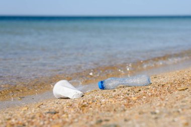 Deniz kıyısındaki plastik çöpler. Şişe seçmeye odaklan. Gün ışığı.