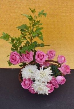 A bouquet of pink roses and white chrysanthemums against a yellow background