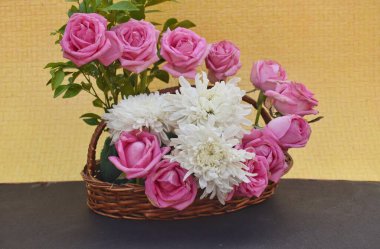 A bouquet of pink roses and white chrysanthemums against a yellow background