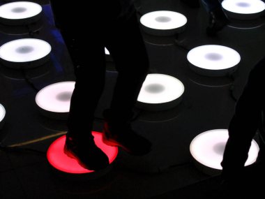 Renkli ışıkların altında dans eden insanların dans ettiği bir sahne..