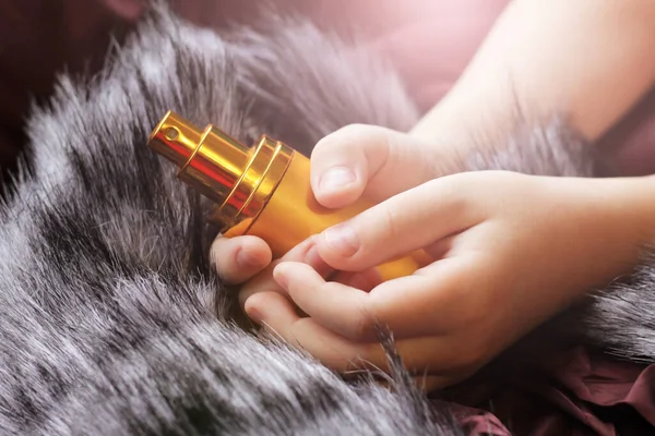 Golden perfume in a child's hand on a fur so close