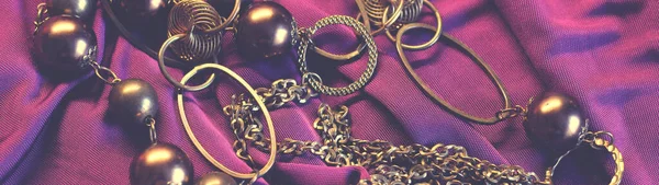 Fine art photo of exclusive jewelry set on purple textile, top view
