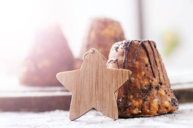 Çikolatalı pasta ve ahşap Noel yıldızı figürü, güneş ışığı