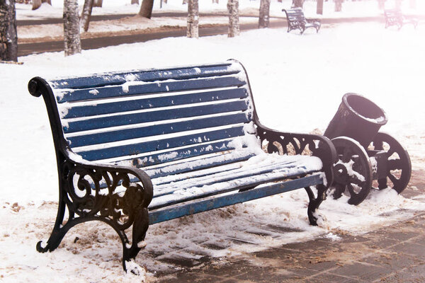 Blue bench in a park covered with snow, nobody