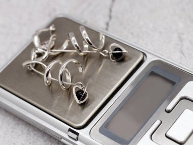 Elektronik pullarda kalpleri olan gümüş küpeler.
