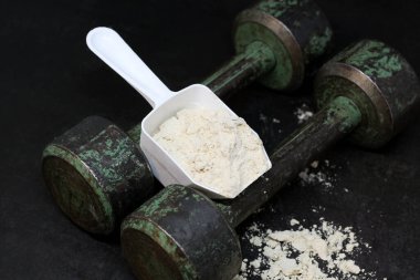 Kaşık içinde kuru protein ve eski demir dambıllar. Spor..