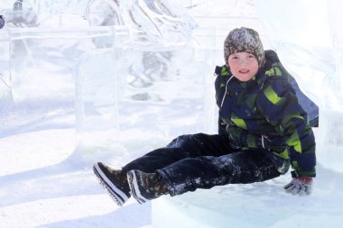 Küçük çocuk kışın buz slayt üzerinde binme keyfini çıkarın. Aile ile çocuklar için açık kış aktiviteleri.