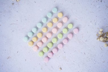 Dokulu bir yüzeyde minyatür pastel makarnalar. El yapımı kil. Dokulu bir yüzeye dizilmiş Pastel Minyatür Makarnalar