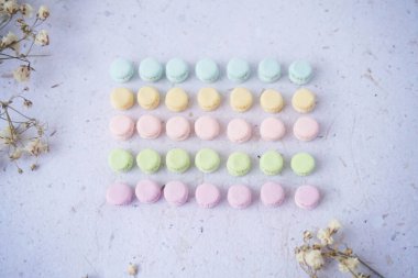 Dokulu bir yüzeyde minyatür pastel makarnalar. El yapımı kil. Dokulu bir yüzeye dizilmiş Pastel Minyatür Makarnalar