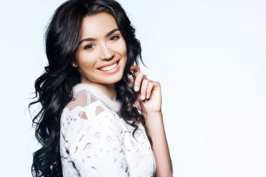 esmer modeli saç ve beyaz bir arka plan üzerinde beyaz bir bluz doğal makyaj ile gülümseyen güzel kız