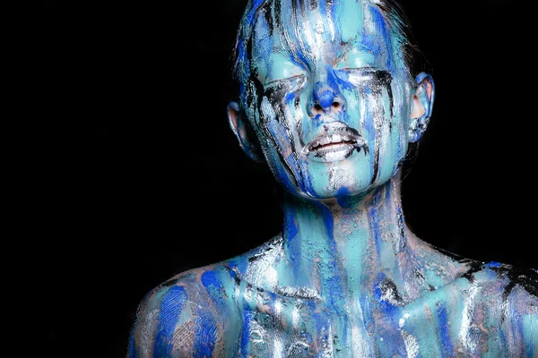 abstract art makeup. Face, neck and hair girls smeared with bright colors of blue, blue and silver colors. The paint flows. On the face of silver tears. Holi festival