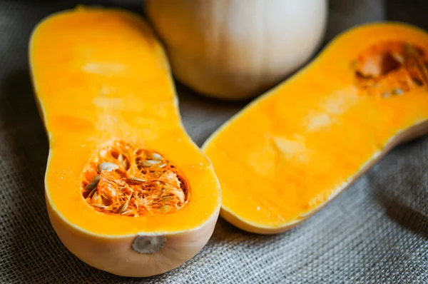 Ungekochter, in Scheiben geschnittener Butternut-Kürbis auf Holzgrund — Stockfoto