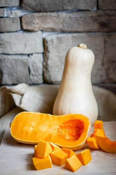 Ungekochter, in Scheiben geschnittener Butternut-Kürbis auf Holzgrund — Stockfoto