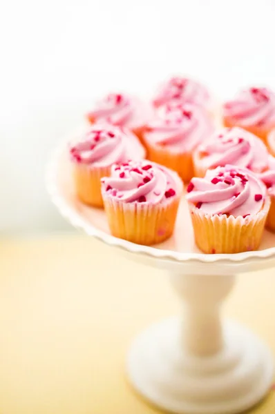 Кексы с розовым кремом и сердечными брызгами — стоковое фото