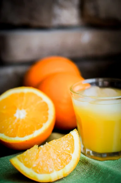 Kieliszek soku pomarańczowego z lodu i plasterki pomarańczy z tyłu drewniane — Zdjęcie stockowe
