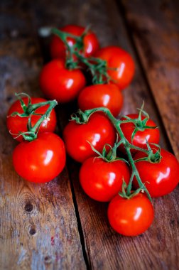 Sarmaşıktaki domatesler ahşap arka planda