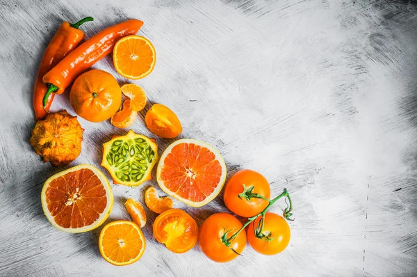 Orange fruits and vegetables on rustic background