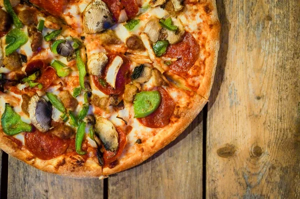ev yapımı biberli pizza rustik ahşap zemin üzerine dilimlenmiş