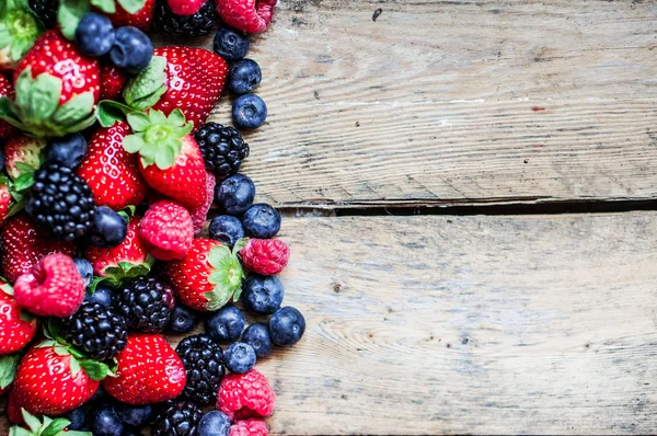 Mischung aus Beeren auf rustikalem Holzgrund — Stockfoto