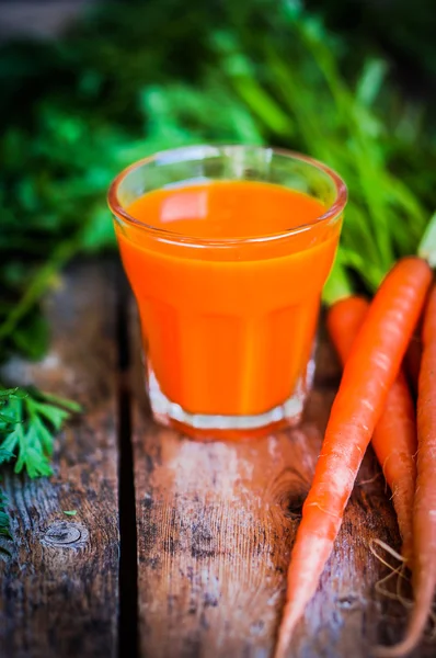 Свежевыжатый морковный сок на деревянном фоне — стоковое фото