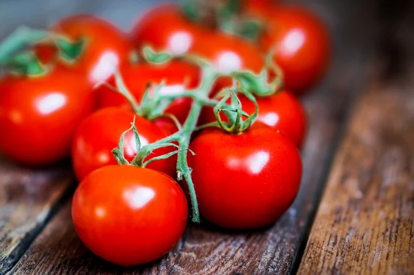 Sarmaşıktaki domatesler ahşap arka planda