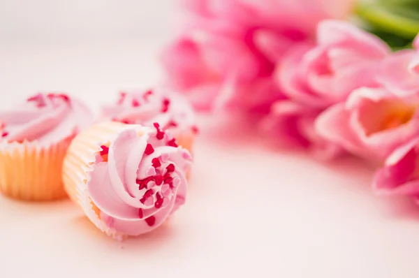 Gâteaux à la crème rose, saupoudrer de cœur et de tulipes sur onglet blanc — Photo