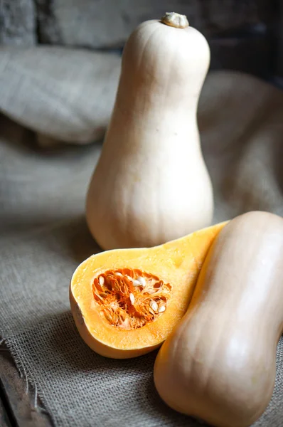 Ungekochter, in Scheiben geschnittener Butternut-Kürbis auf Holzgrund — Stockfoto