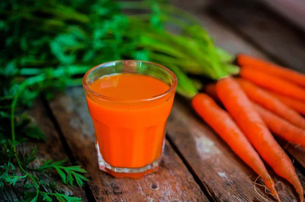 Fresh-squeezed carrot juice on wooden background — Stock Photo, Image