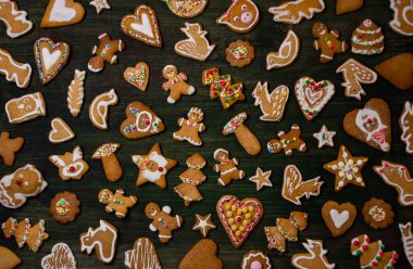 Düzenleme, mevsimsel cazibeyi ön plana çıkarıyor. Ahşap zeminde süslü zencefilli ekmek çeşitleri. Renkli krema tuhaf el yapımı görünümü güçlendirir. Manzara neşeli bir tatil ruhunu çağrıştırıyor..