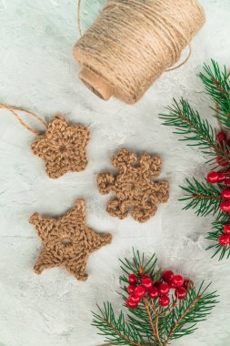 Noel keneviri işlemeli kar taneleri, köknar dalları ve beyaz arka planda kırmızı böğürtlenler. Tığ işi dekor üst görünümü.
