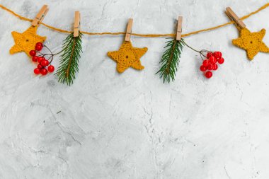 Noel kompozisyonu parlak bir çelenkle örülmüş sarı yıldızlar, köknar ağacı dalları ve kırmızı böğürtlenlerden yapılmıştır..