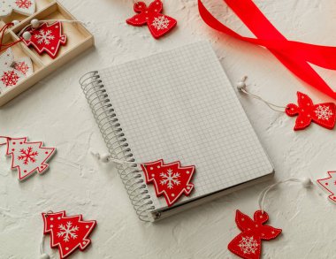 Not defteri olan bir Noel kompozisyonu, beyaz arka planda Noel oyuncakları.