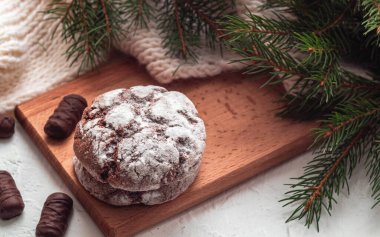 Tahta bir tahtada çikolata tozlu kurabiye ve çikolata ve Noel ağacı dalları. Geleneksel çikolatalı kek..
