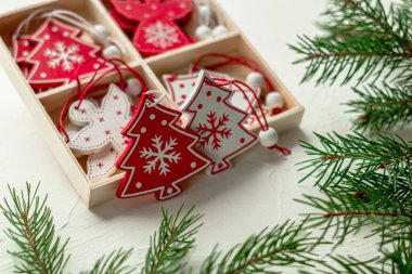 Noel ağacında beyaz arka planda bir kutuda Noel ağacı oyuncakları. Kırmızı ve beyaz tahta oyuncaklar.