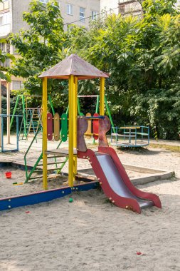 İçinde slaytlar, tırmanma yapıları ve huzurlu bir konut avlusunda duran bir kum havuzu olan boş bir oyun alanı, günlük çocukluk zamanlarını yansıtıyor..