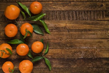 Ahşap arka planda yeşil yapraklı parlak mandalinalar, doğal meyveyi, sadeliği ve sağlıklı yaşamı temsil ediyor. Boşluğu kopyala.