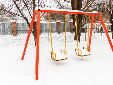 Karla kaplı salıncak, soğuk mevsimlerde oyun alanının sakin atmosferini yakalayarak kış bahçesinde boş duruyor..