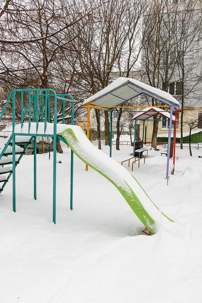 Karla kaplı kaydırak seti, soğuk mevsimde sakin bir sessizlik ve duraklayan çocukluk oyununu gösteren bir kış oyun parkında boş duruyor..