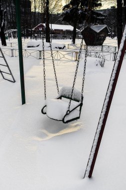 Bir oyun parkında taze kara gömülü boş salıncak. Kış mevsimini, yalnızlığı ve buz gibi havayı sembolize ediyor..