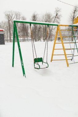 Karlı oyun parkı, soğuk iklimi, sakin havayı ve kış mevsiminde çocukluk zamanlarını yansıtan insansız salıncaklar..