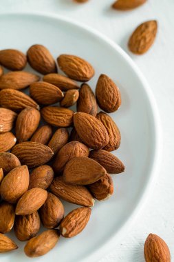 Beyaz arka planda bademler olan bir tabak sağlıklı yaşam, dikkatli beslenme ve temiz yeme, denge taşıma, basitlik ve bilinçli yaşam tarzı seçimlerini sembolize eder..