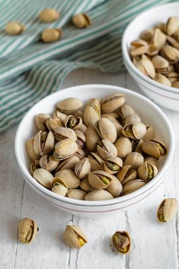 Beyaz ahşap bir masaya yerleştirilmiş kavrulmuş şam fıstığı. Basit ve parlak kompozisyonu olan sağlıklı atıştırmalık konsepti..