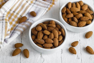 Beyaz seramik kaselerde badem atıştırmalığı, ahşap masa dokusuyla temiz yemek fotoğrafçılığı..