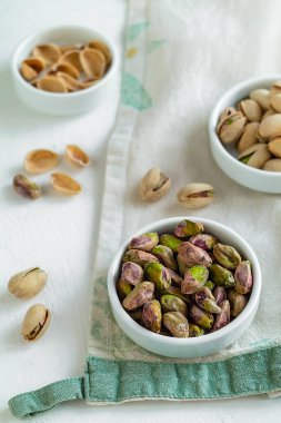 Seramik kaselerde sağlıklı şam fıstığı atıştırmalıkları ahşap masada keten kumaş, bitki bazlı beslenme ve temiz yeme konsepti..