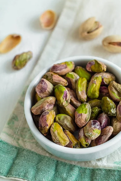 Aperatifler için hazır yeşil fıstıklar, hafif mutfak arka planında küçük kaseler halinde dizilmiş..