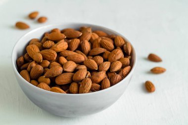 Beyaz arka plandaki bir kasedeki badem besinleri, sürdürülebilir gıda seçimlerini ve günlük beslenmeye özenli bir yaklaşımı simgeler. Boşluğu kopyala.