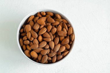 Beyaz arka planda izole edilmiş en az kâse badem doğal beslenme, sağlık alışkanlıklarını ve sağlıklı gıdalara ve günlük özbakıma modern bir yaklaşımı temsil ediyor. Boşluğu kopyala.