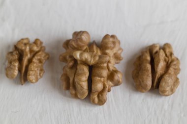 Organik beslenme, yemek malzemeleri ve sağlıklı yaşam temaları için beyaz, basit besin imgesine izole edilmiş üç ceviz çekirdeğinin yakın çekim görüntüsü.